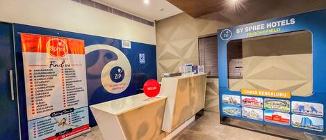 A hotel reception area with a reception desk, a large Spree Hotels sign, and a wall with a map and pictures of local attractions.