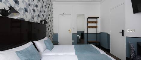 A modern hotel room with a large bed, a flat-screen TV, a ceiling fan, and a bathroom visible through an open door.