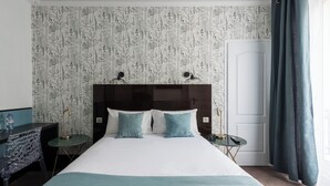Una habitación de hotel con una cama grande, dos mesitas de noche, un escritorio y una silla.