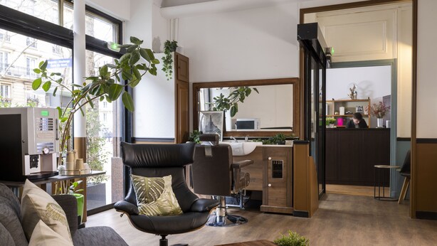 Una sala de estar moderna con un sofá, un sillón de cuero negro, una mesita de centro y un ventanal grande.