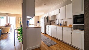 A modern kitchen with white cabinets, a wooden countertop, and a built-in microwave. - Bayside Apartment #4- Top Floor Waterfront Views above Boulevard Park (Bellingham)