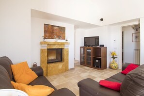 Un salon avec une cheminée, un téléviseur et un canapé agrémenté de coussins.