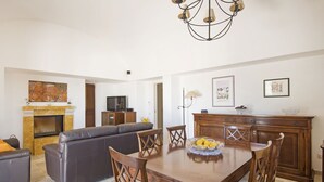 A living room with a fireplace, a sofa, a dining table with chairs, and a chandelier. - Hillside villa with pool for 5 guests in Monopoli (Monopoli)