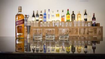 Un bar con una botella de whisky Red Label y varios vasos sobre una superficie reflectante.