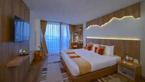 A modern hotel room with a large bed, a desk, a flat-screen TV, and a view of the city. - Aabas Pokhara by Barahi Hospitality (Pokhara)
