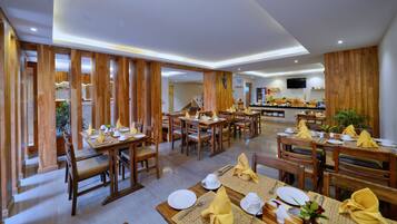 Un restaurante con decoración de madera, varias mesas dispuestas con servilletas amarillas, platos blancos y cubiertos.