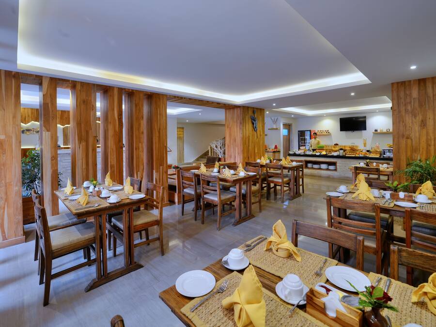 Un restaurante con decoración de madera, varias mesas dispuestas con servilletas amarillas, platos blancos y cubiertos.