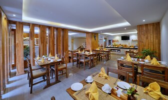 Un restaurante con decoración de madera, varias mesas dispuestas con servilletas amarillas, platos blancos y cubiertos.