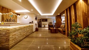 A hotel reception area with a stone counter, wooden paneling, a clock, and a staircase leading to the upper floor. - Aabas Pokhara by Barahi Hospitality (Pokhara)