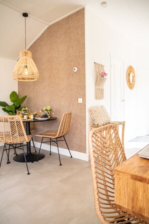 A dining area with wicker chairs, a round table, and a hanging light fixture.