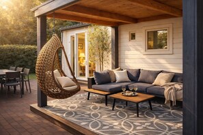 A cozy outdoor seating area with a hanging chair, a sofa, and a coffee table. - StayatSas Tiny House Sam. Free WiFi, reserved parkingspace, kids & dogs welcome! (Epe)