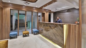 Een moderne receptiebalie met een marmeren toonbank, houten details en een glazen scheiding.