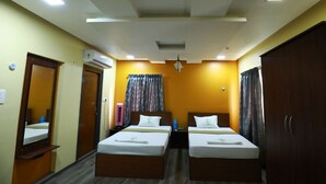 Une chambre d’hôtel avec deux lits, une armoire, un miroir, un appareil de climatisation et un ventilateur de plafond.