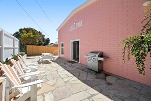 Un espacio al aire libre con piso de piedra, una parrilla y mobiliario exterior.