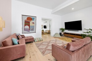 Una sala de estar moderna con un conjunto de sofás, un televisor de pantalla plana y un cuadro abstracto grande en la pared.