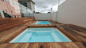 A rooftop swimming pool with wooden decking and a clear blue pool.