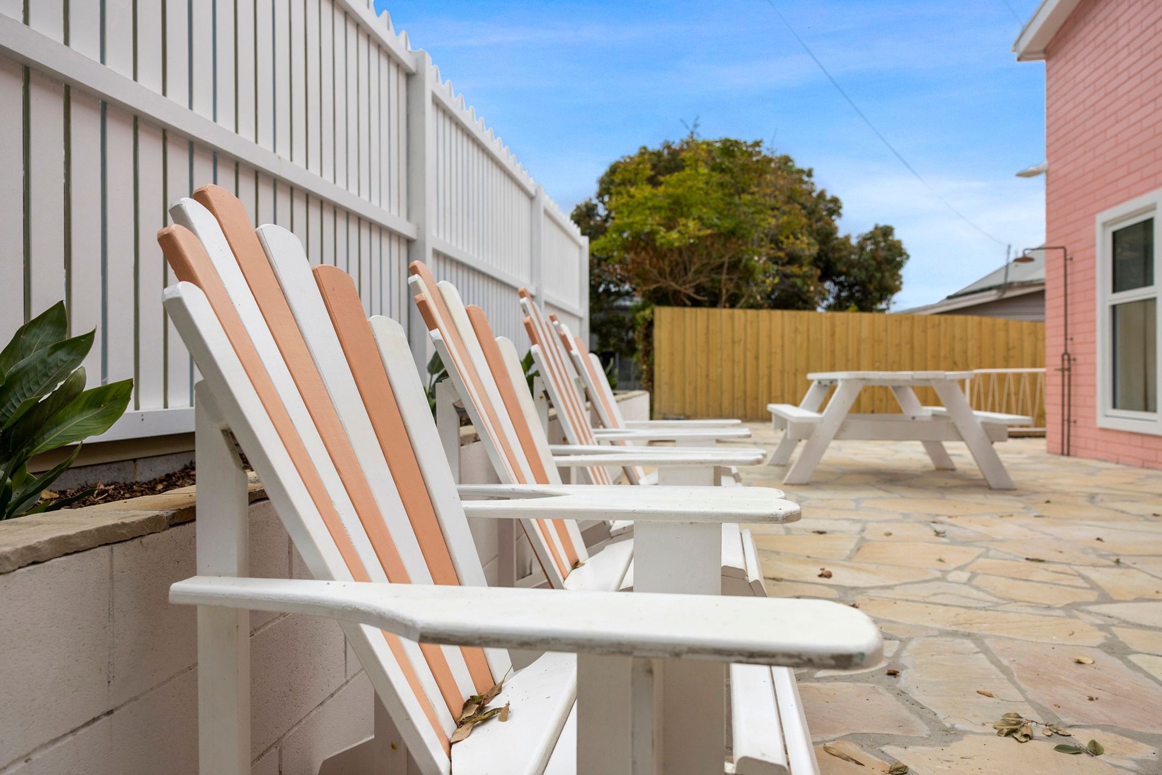 Outdoor seating with white and peach chairs, a picnic table, and a stone patio.