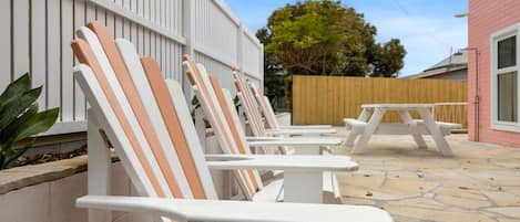 Outdoor seating with white and peach chairs, a picnic table, and a stone patio.