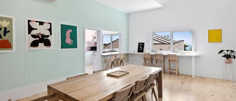 A modern kitchen with a dining area, wooden furniture, and artwork on the walls.