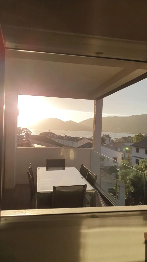 A modern room with a large window overlooking a coastal view during sunset. - Spacious, bright apartment by the harbor for 4 to 6 people (Porto-Vecchio)