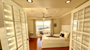 A bedroom with a bed, a ceiling fan, and a view of the water outside.