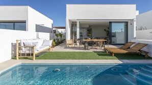 Ein modernes Haus mit Swimmingpool, Gartenmöbeln und einer Terrassenfläche.