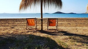 Eine Strandansicht mit einem Reetdachschirm und zwei Stühlen.