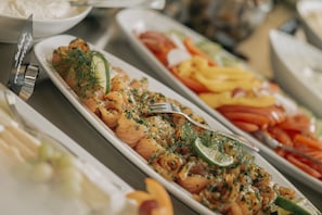Ein Buffet mit verschiedenen Speisen, darunter Lachs, Gemüse und Salat.