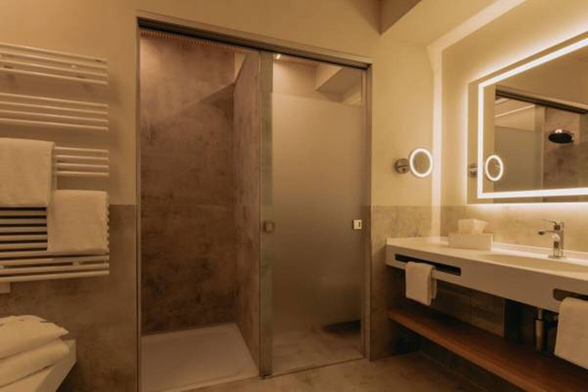 Un baño moderno con cabina de ducha de vidrio, tocador con espejo y un perchero para toallas.
