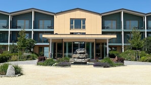 A multi-story hotel with a central entrance, balconies, and a landscaped garden area. - Landhotel Bohrerhof (Hartheim am Rhein)