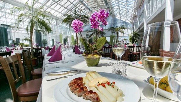 A restaurant with a glass ceiling, white tablecloths, and purple napkins. - Landhotel Bohrerhof (Hartheim am Rhein)