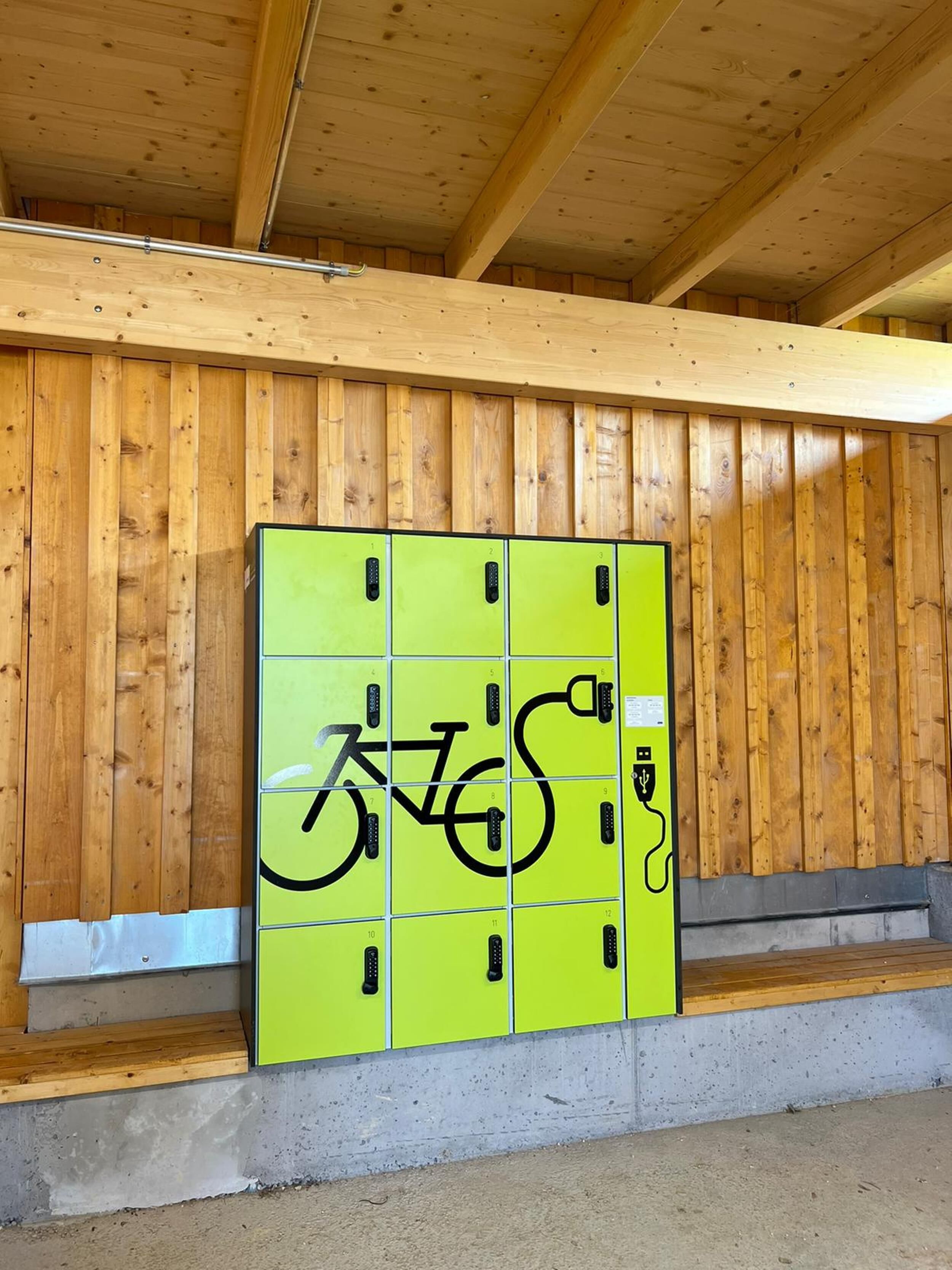 A row of lockers with a bicycle symbol painted on them, set against a wooden wall.