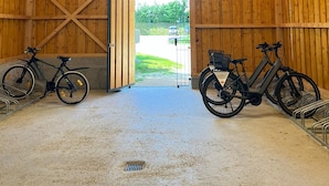 A wooden barn with a large open door leading outside. Inside, there are two bicycles parked near the door. - Landhotel Bohrerhof (Hartheim am Rhein)