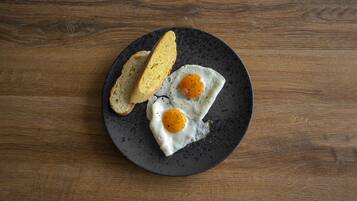 A plate with two fried eggs and two slices of toast on a dark plate.