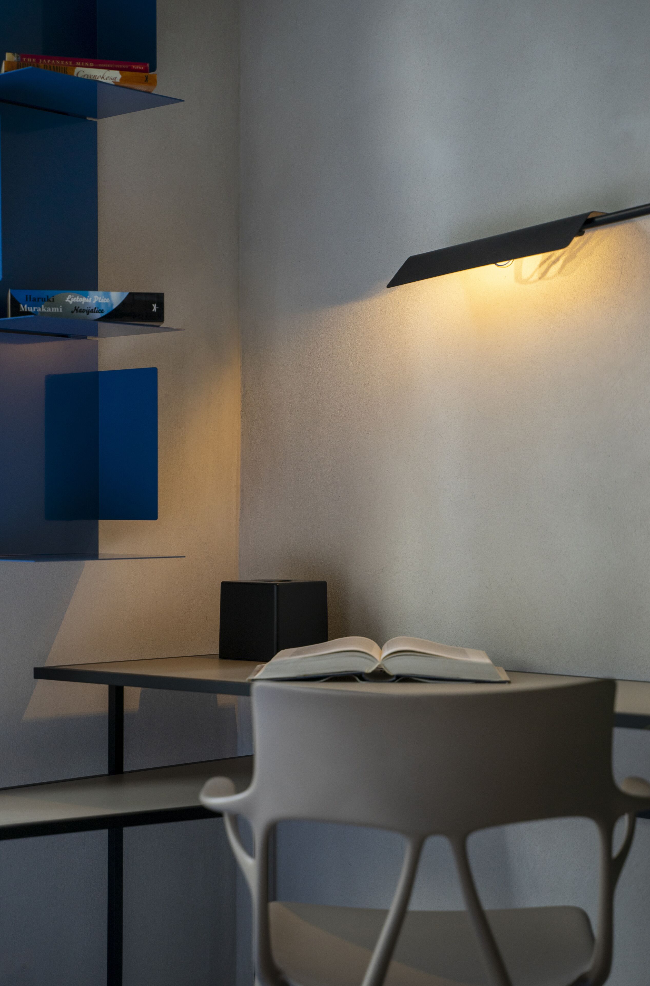 A modern room with a desk, a chair, and a bookshelf.