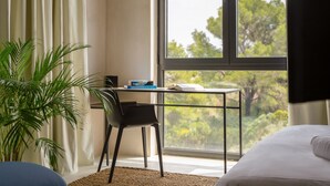 A room with a bed, a desk with a chair, a large window, and a plant. - Moro Inn  (Korcula)