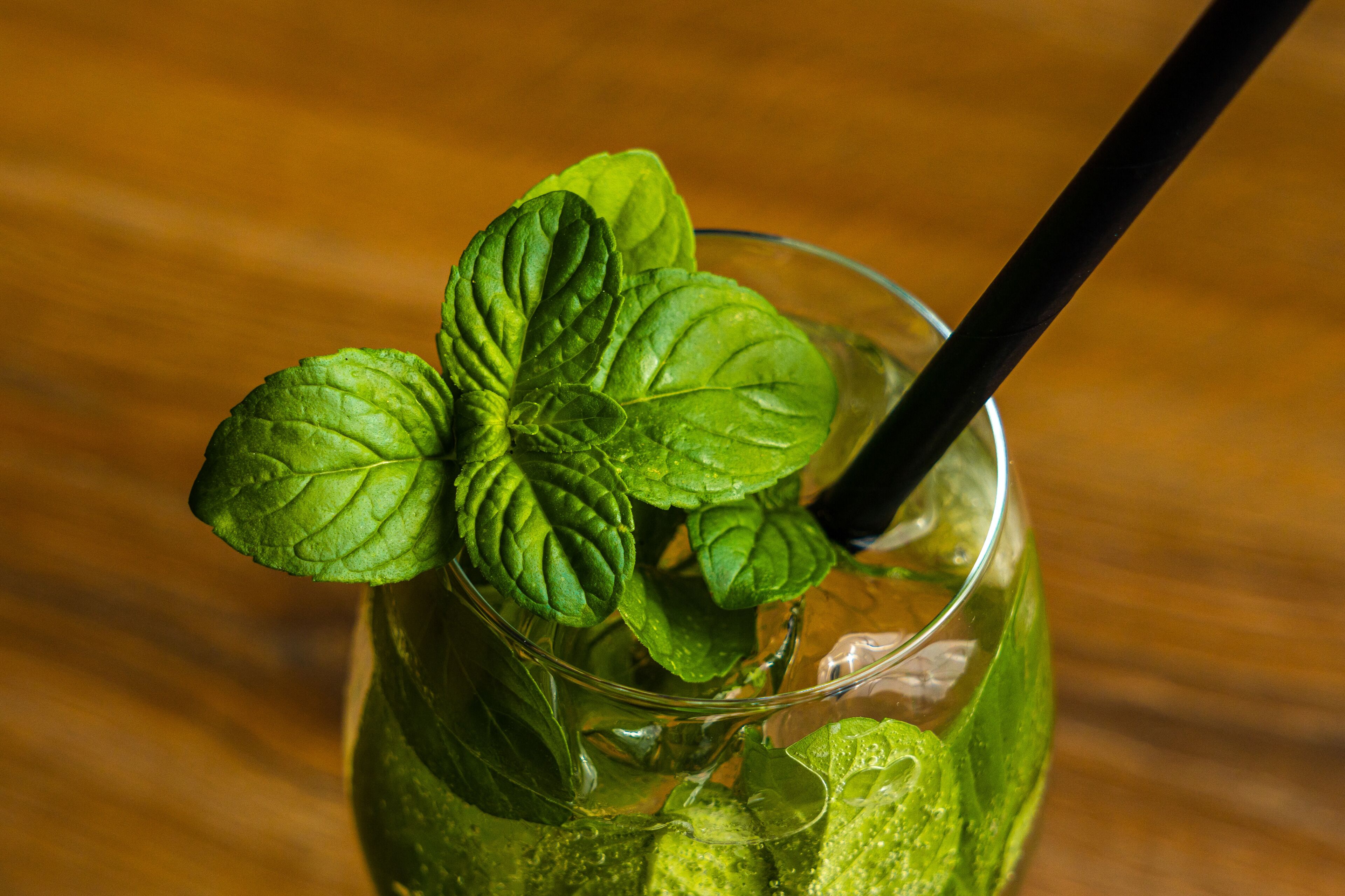 A glass with mint leaves and a straw.