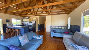 A spacious living area with a wooden ceiling, a kitchen with a central island, and a seating area with a sofa and a couch. - After Dune Delight, Indulge in your Ocean views. (Inverloch)