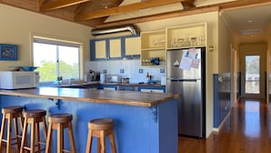 A modern kitchen with a central island, bar stools, stainless steel appliances, and a view of the outdoors. - After Dune Delight, Indulge in your Ocean views. (Inverloch)