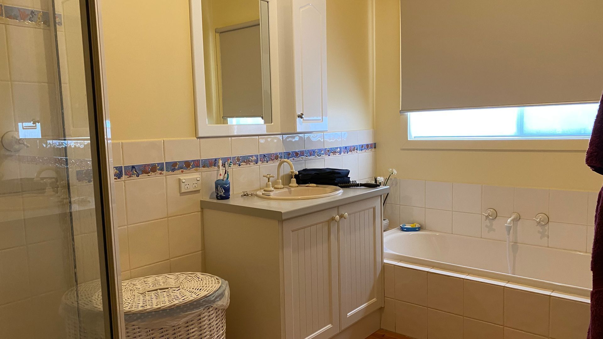 Une salle de bain avec une baignoire, un lavabo, un miroir et une fenêtre.