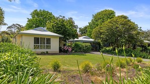 A two-story house with a well-maintained lawn and garden. - Surf Mist Retreat (Inverloch)