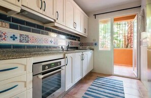 Enjoy cooking in this kitchen with oven, tile backsplash, and balcony access.