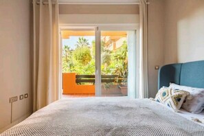 Relax in a serene space with a large bed and sliding door to an outdoor area with lush greenery.
