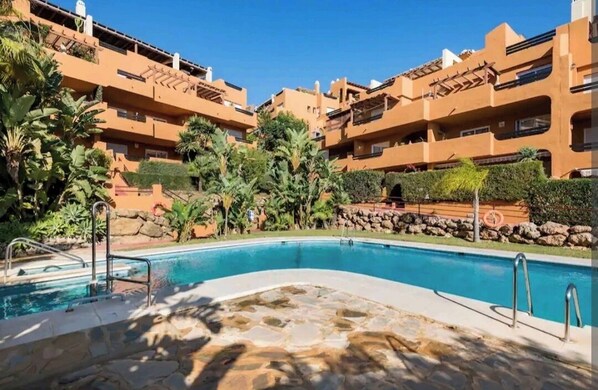 Relax by the pool surrounded by lush greenery and palm trees.