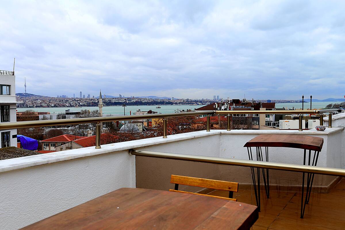 A rooftop terrace with a view of a cityscape, including a prominent tower.