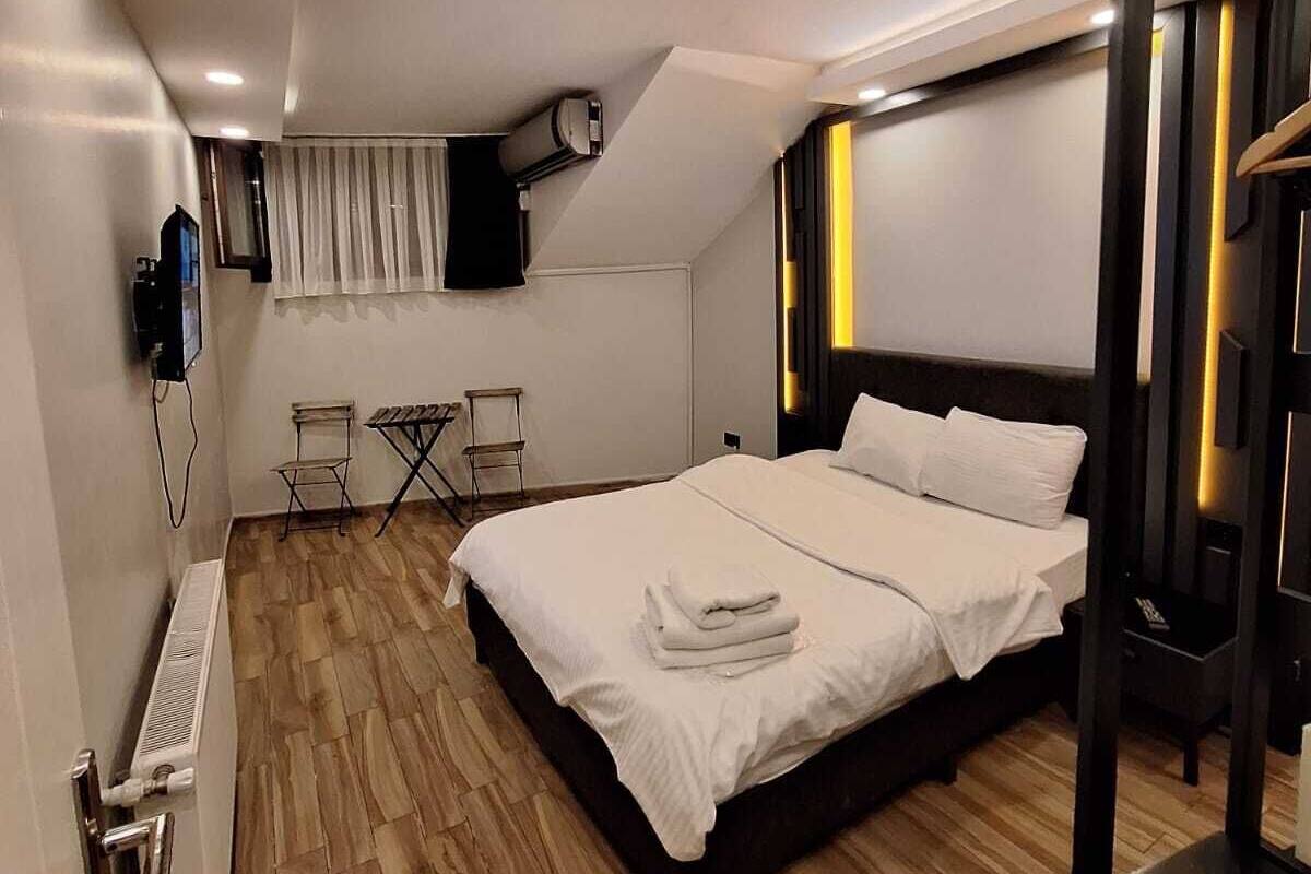 A modern bedroom with a large bed, a radiator, a TV, and a small seating area.