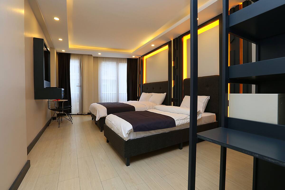 A hotel room with two beds, a desk, and a chair.