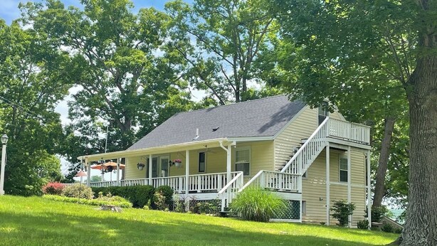A two-story house with a porch and a staircase leading to the second floor. - 4 Bedroom Comfortable Cottage (Versailles)