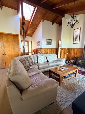 A cozy living room with a large sectional sofa, a wooden coffee table, and a fireplace. - Canyon Cottage ~ Majestic view (Blackheath)
