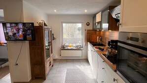 A modern kitchen with white cabinets, a large window, and a built-in oven.